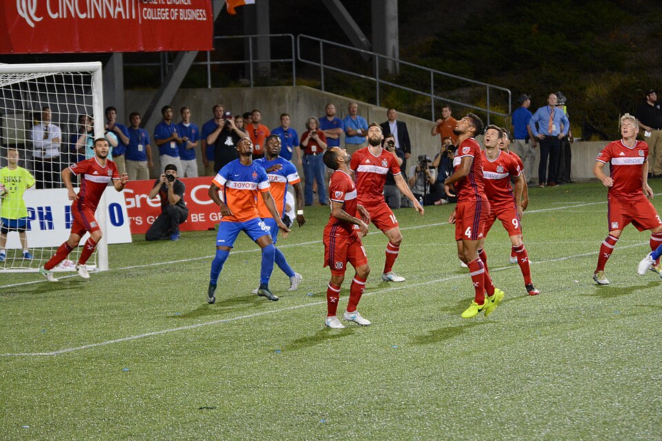 Cobro de tiro de esquina en un partido de fútbol bajo luces
