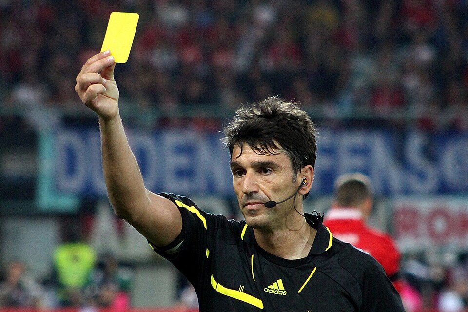 Árbitro mostrando tarjeta amarilla en un partido de fútbol